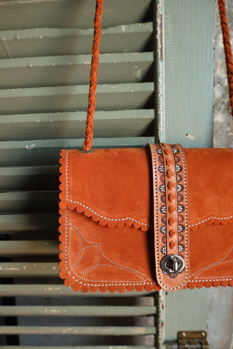 Orange leather rectangle handbag with scallop detail on boarder, boot stitch detail on body of bag and center leather strap with floral hand tooling and twist lock closure