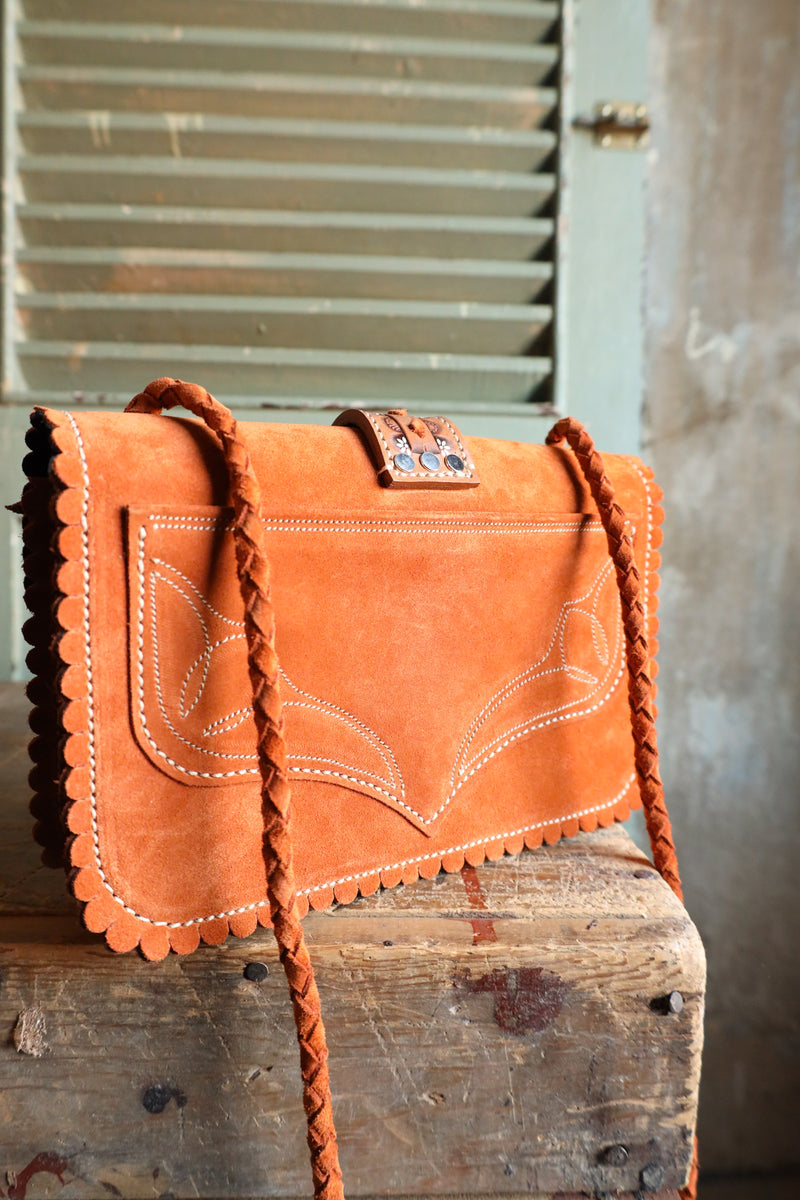 Orange leather rectangle handbag with scallop detail on boarder, boot stitch detail on body of bag and center leather strap with floral hand tooling and twist lock closure