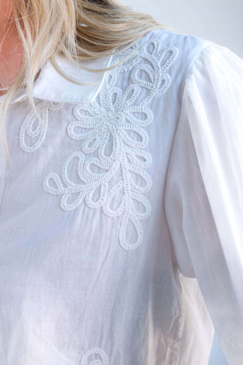 White blouse with intricate lace detailing on a blurred background