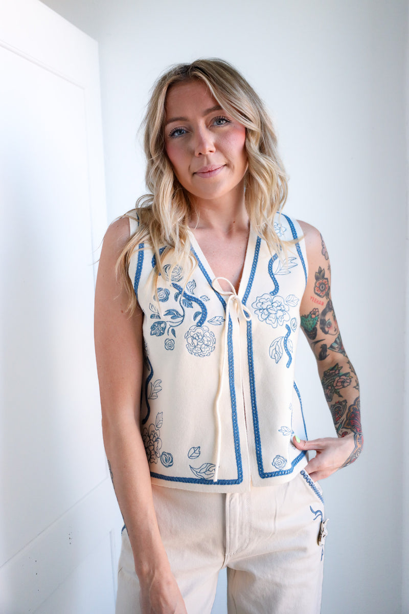 Woman wearing a sleeveless top with floral patterns against a white background