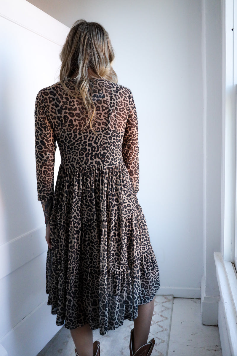 Person wearing a leopard print dress in a minimal indoor setting