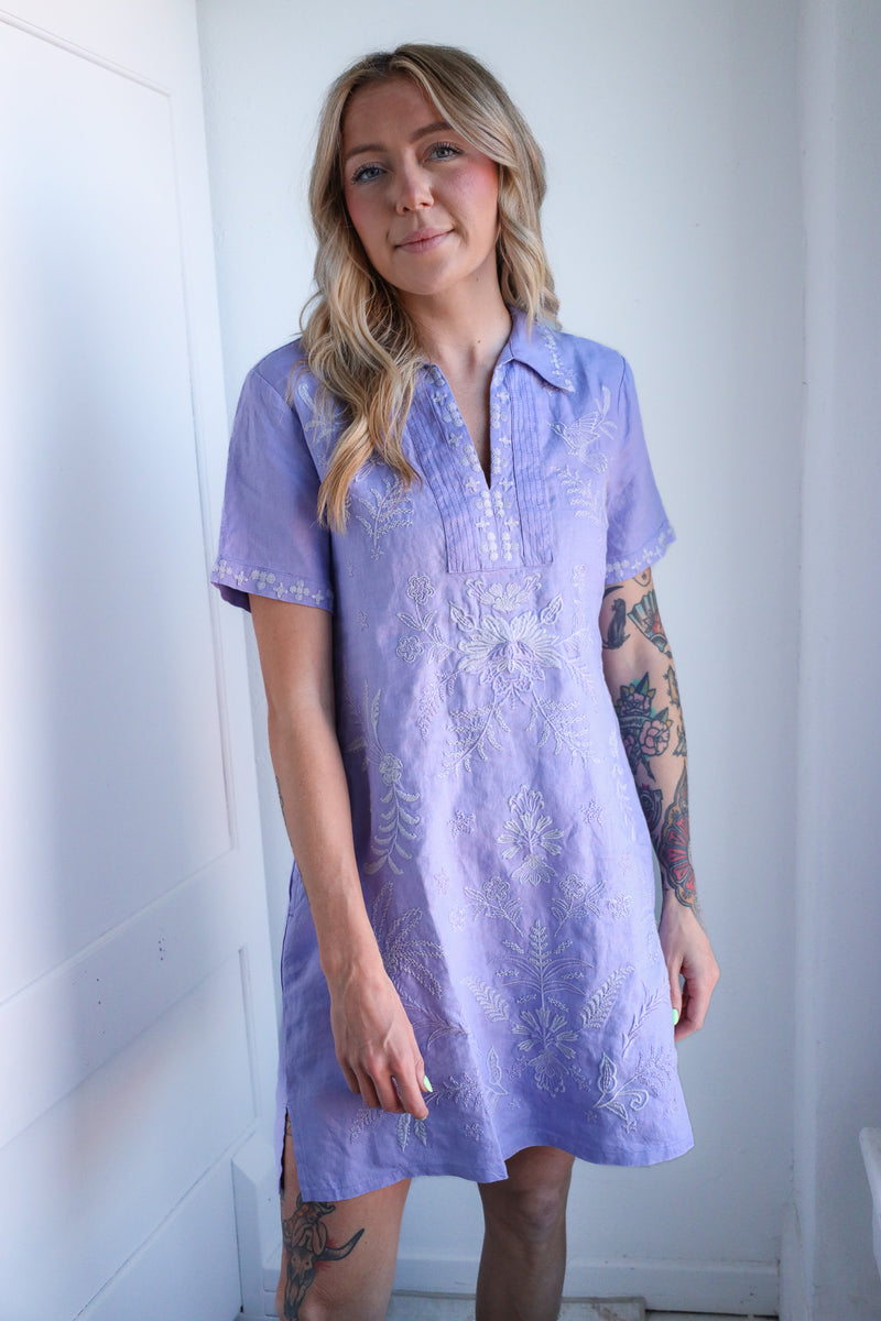 Woman wearing a light purple dress with lace details against a white background