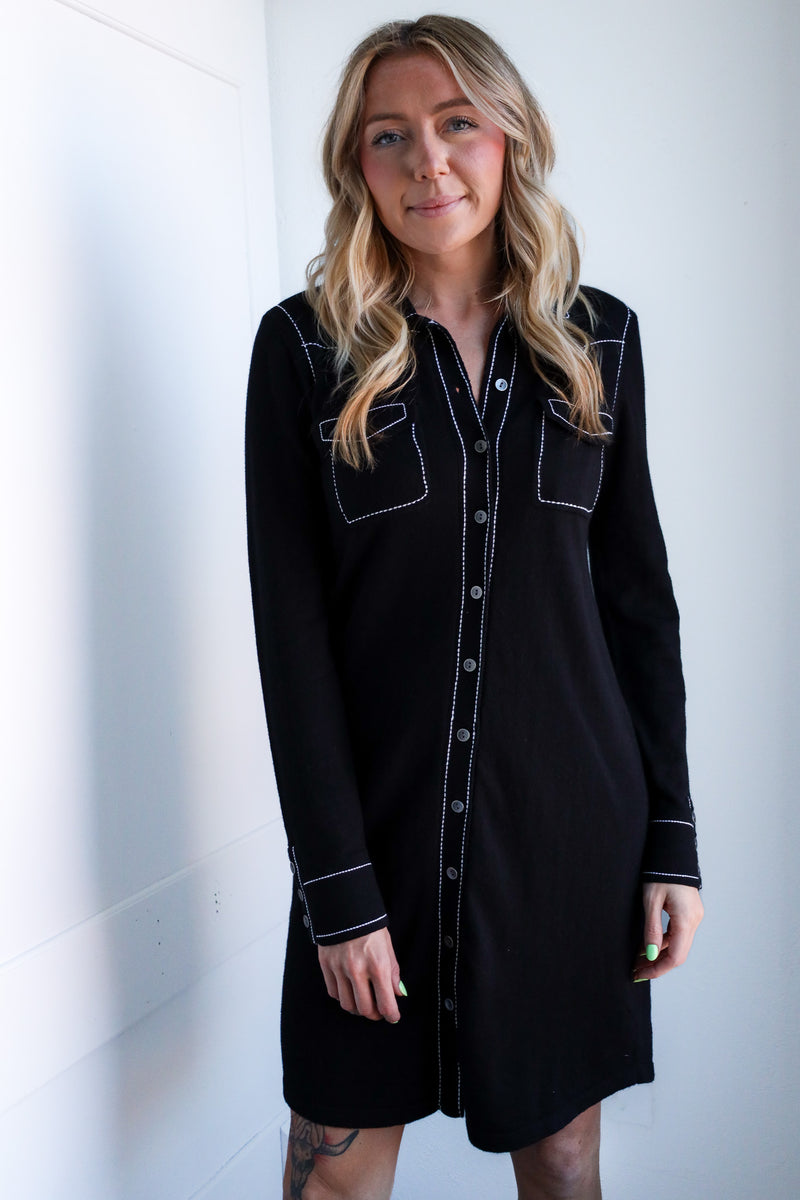Woman wearing a black dress with white trim against a white background