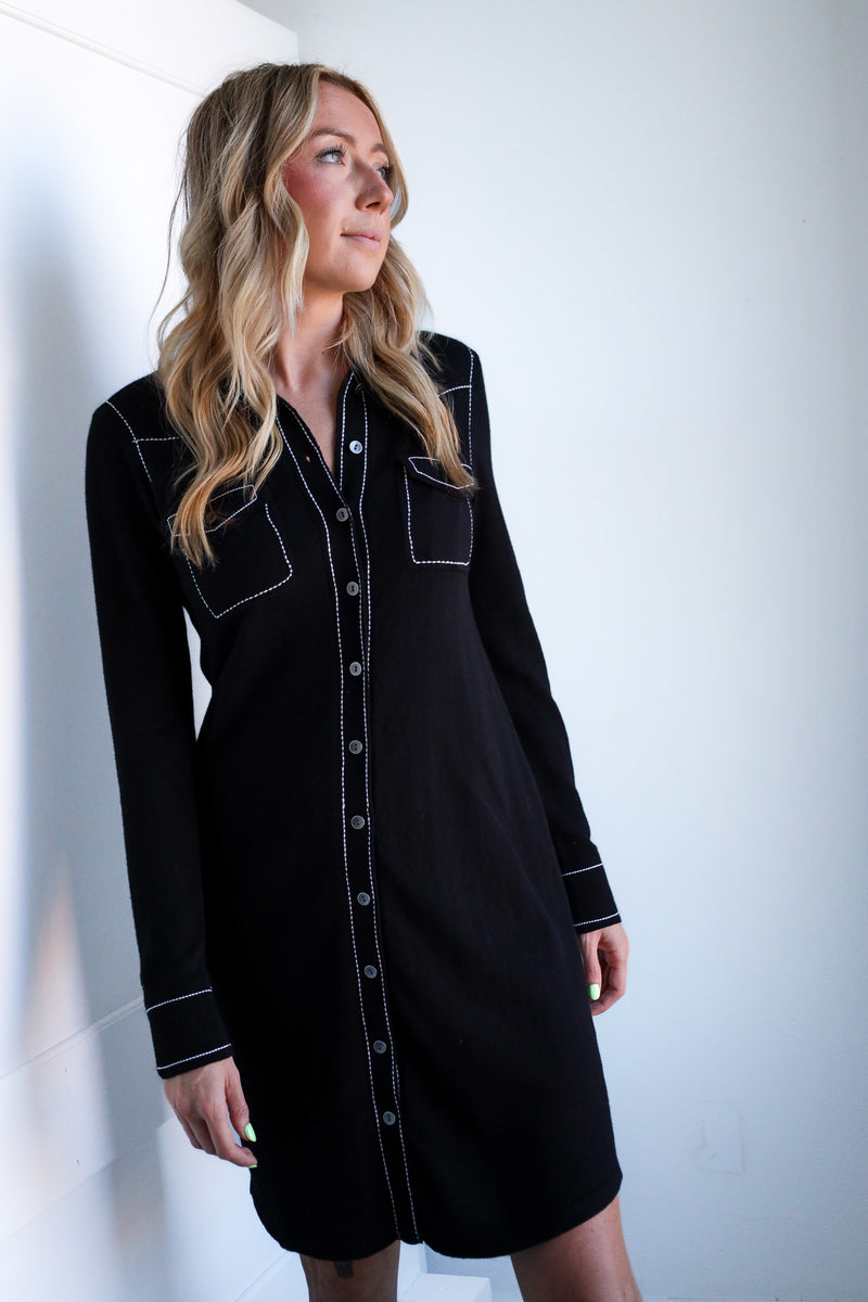 Woman wearing a black dress with white trim against a white background
