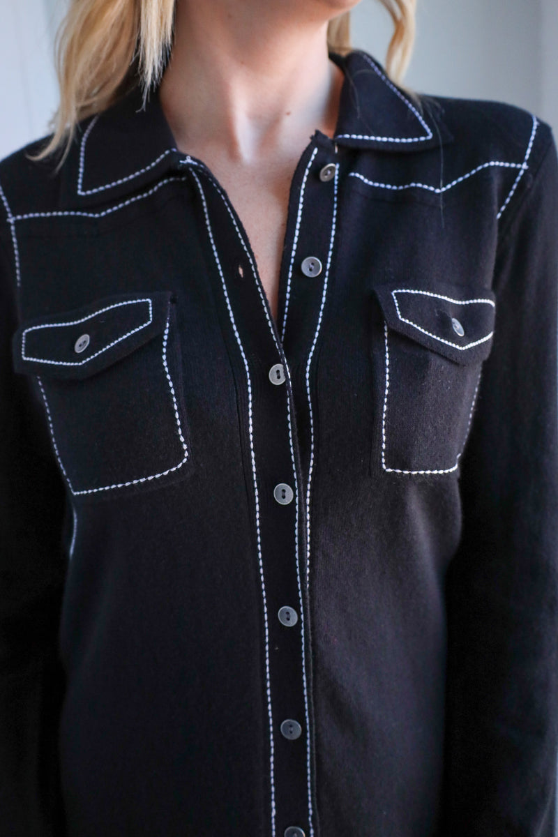 Black shirt with white stitching on a plain background