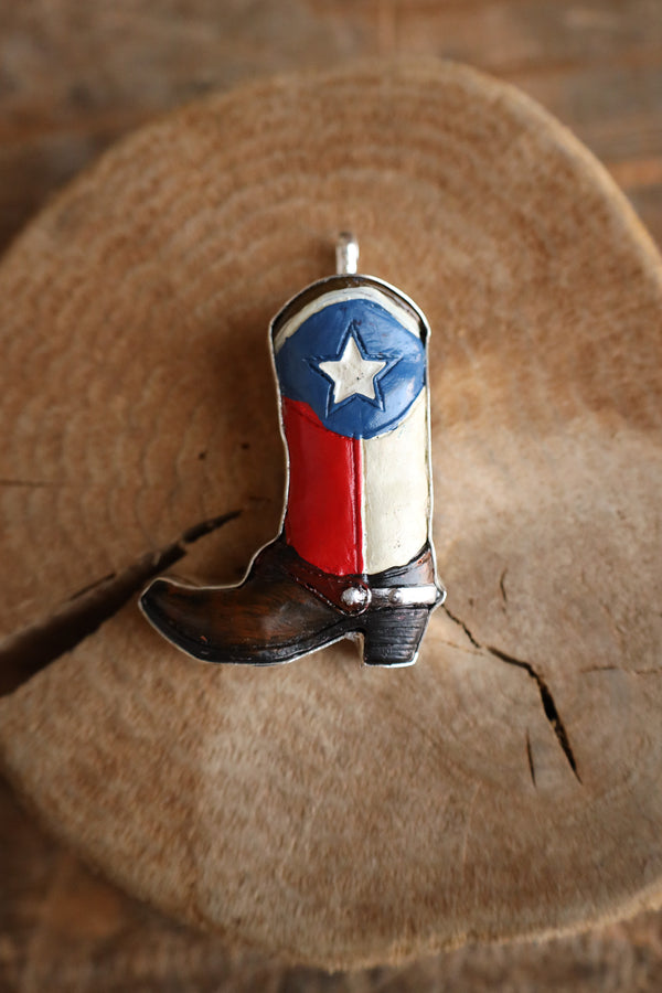 Cowboy boot pendant with Texas flag design on a wooden surface