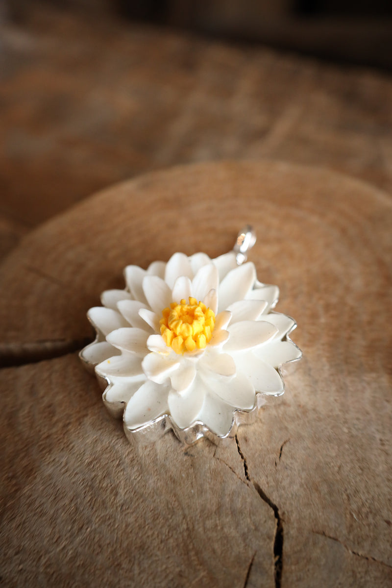 White flower-shaped object with a yellow center on a wooden surface