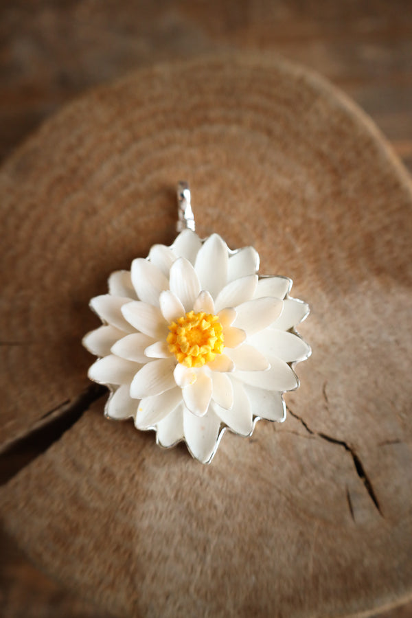White flower-shaped pendant on a wooden surface