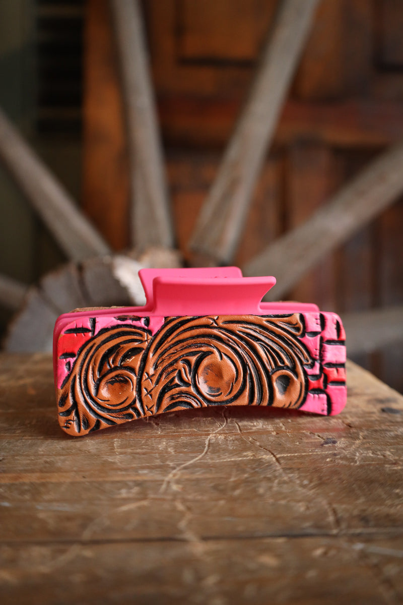 Pink and brown patterned clutch bag on a wooden surface with blurred background