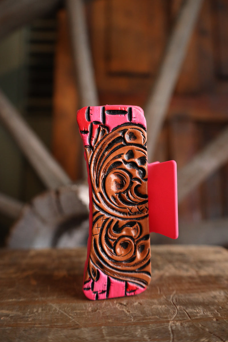 Phone case with pink border and intricate brown design on a wooden surface