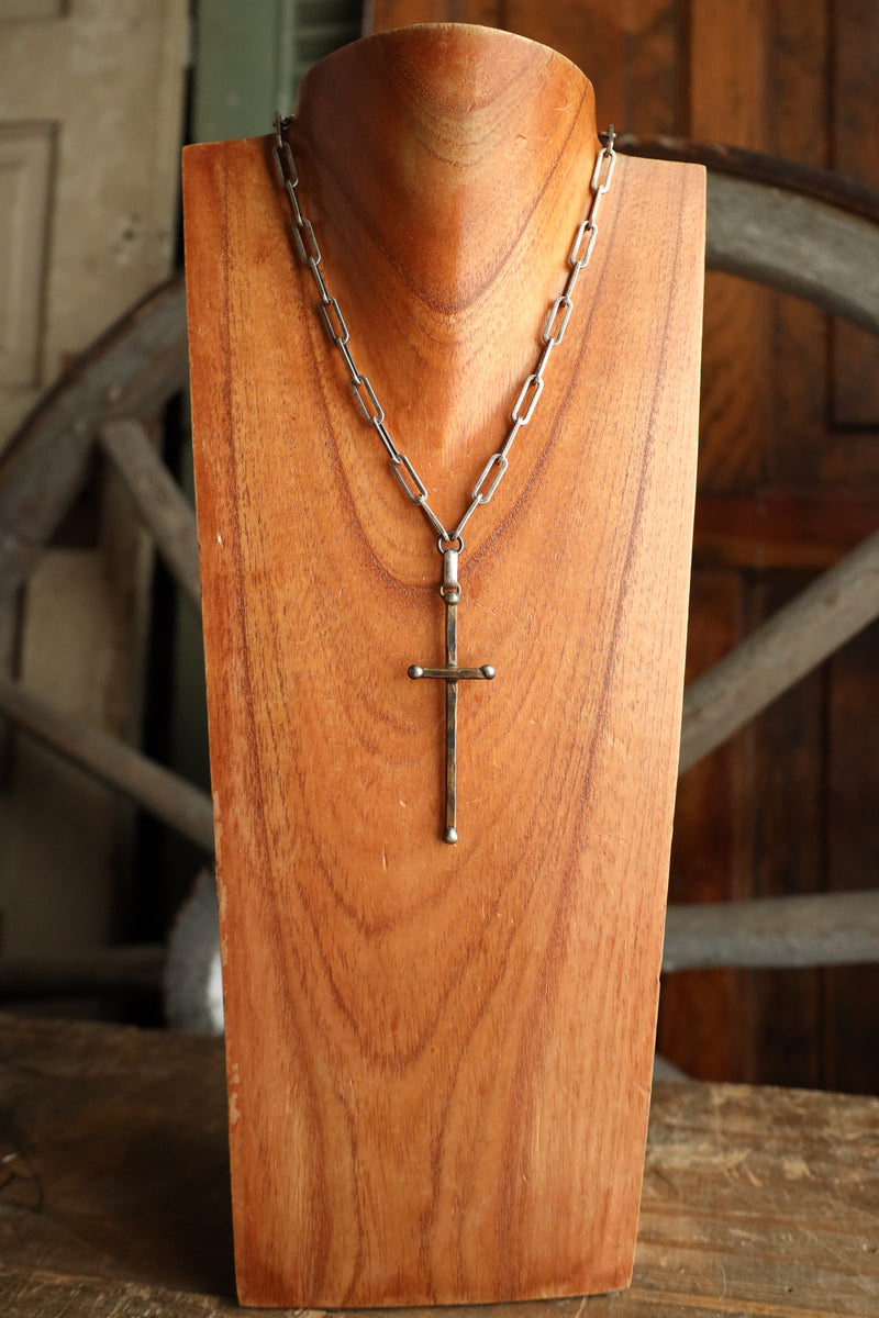 Necklace with a cross pendant on a wooden stand with a rustic background