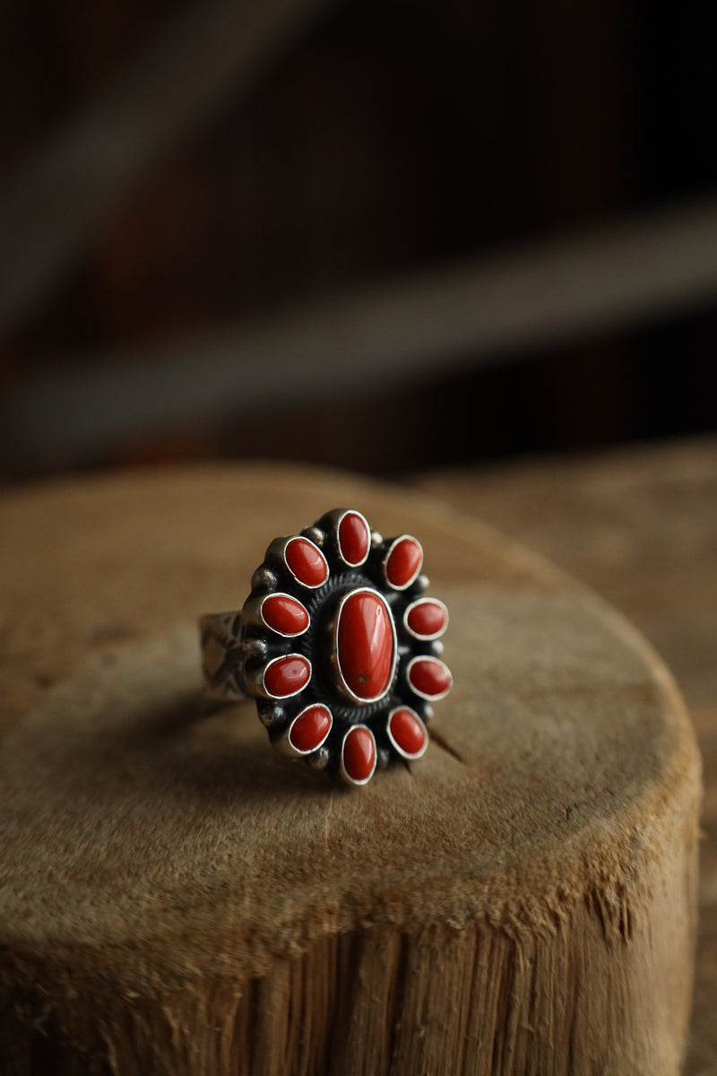 Silver ring with red stones on a wooden surface