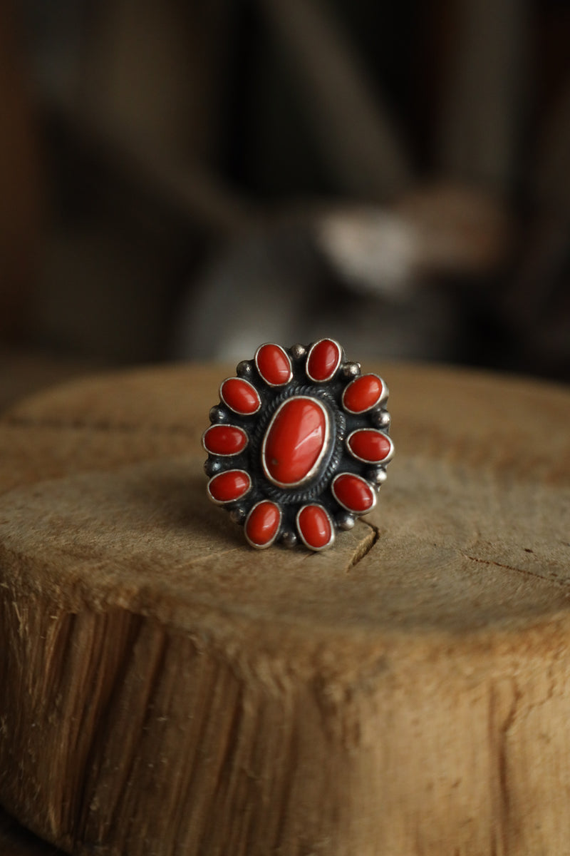 Silver ring with red stones on a wooden surface