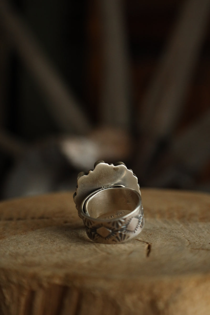 Silver ring with intricate design on a textured surface