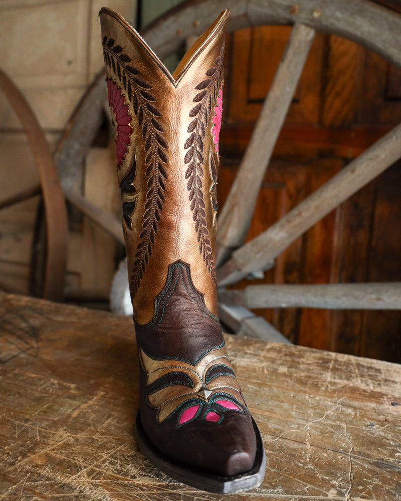 Decorative cowboy boot with intricate designs on a wooden surface.