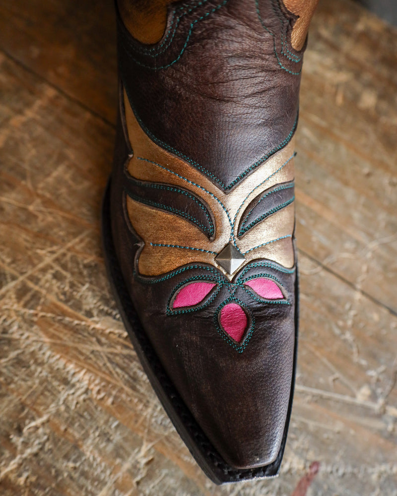 Close-up of a brown leather boot with decorative patterns on a wooden surface