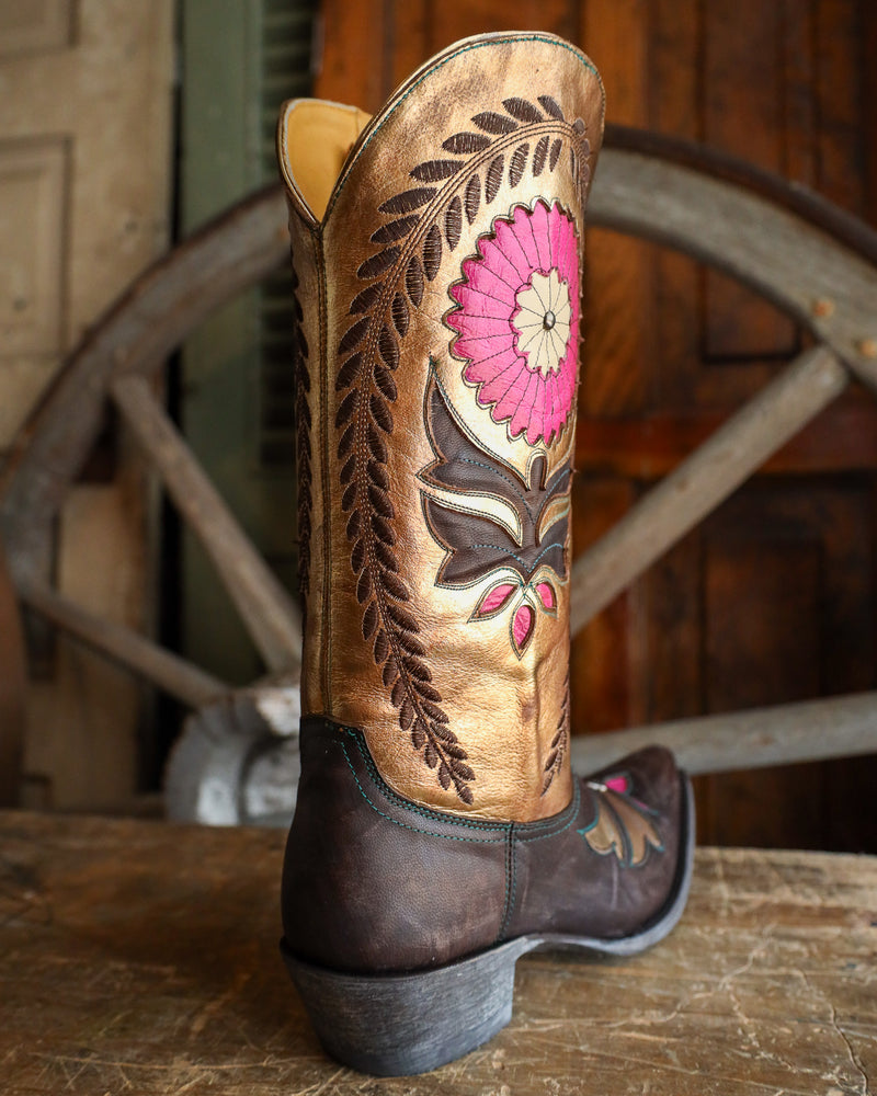 Brown cowboy boot with floral embroidery on a wooden surface