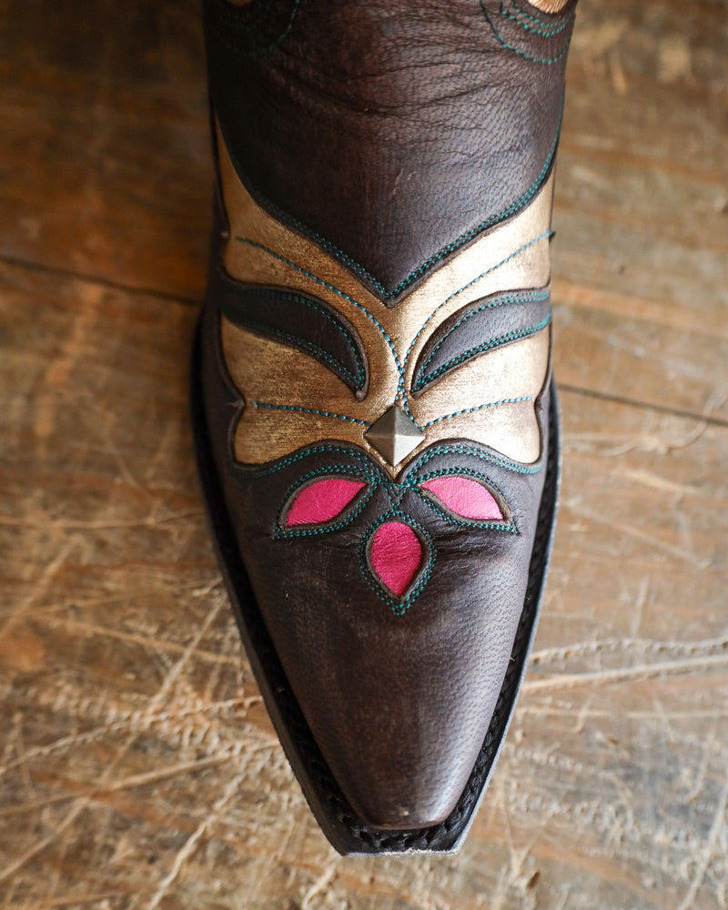 Brown leather boot with decorative patterns on a wooden floor