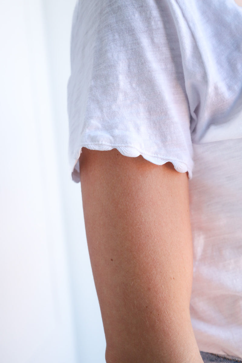 White t-shirt with a small tear on the shoulder against a white background