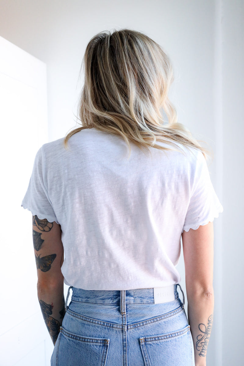 Person wearing a white t-shirt and blue jeans with a plain background