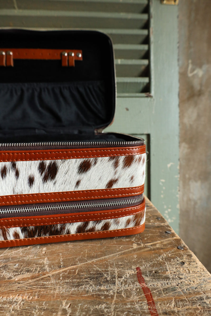 Double decker jewelry case with cowhide exterior and leather tooling and includes travel strap