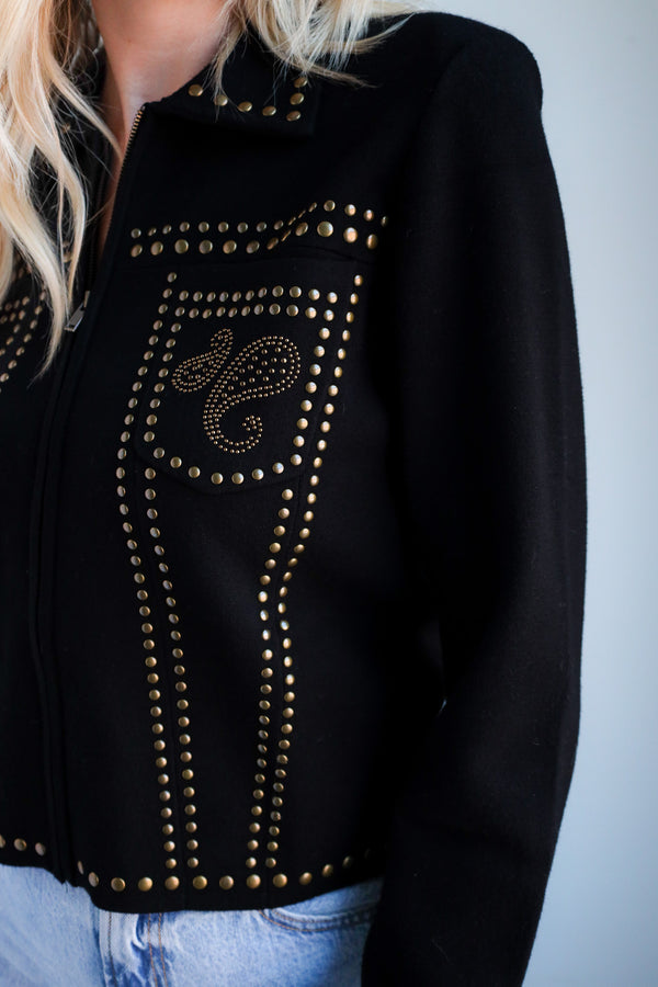 Black jacket with gold studs and a decorative design on a plain background