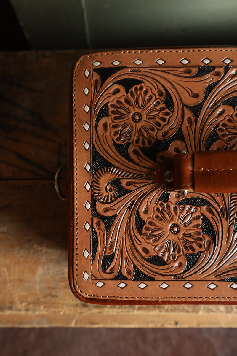 Double decker jewelry case with cowhide exterior and leather tooling and includes travel strap