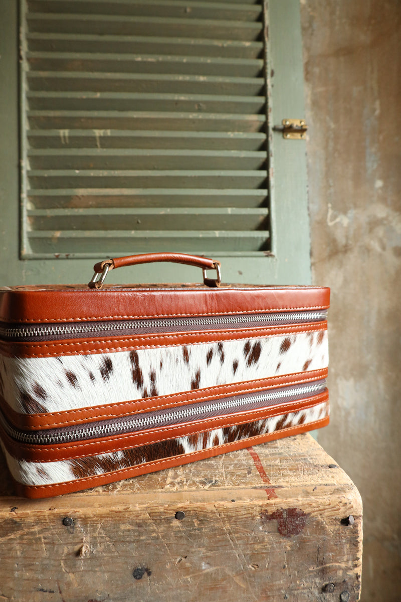 Double decker jewelry case with cowhide exterior and leather tooling and includes travel strap