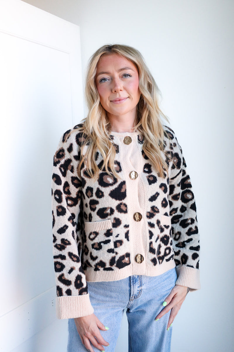 Woman wearing a leopard print cardigan and light blue jeans against a white background