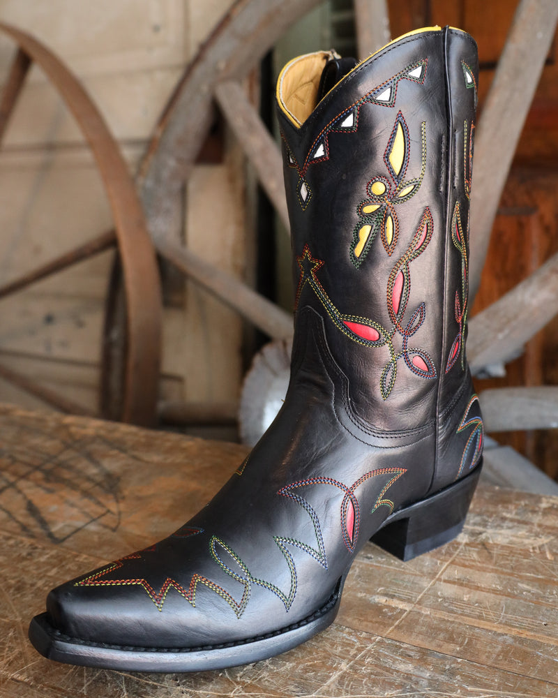 Black cowboy boot with colorful embroidery on a wooden surface