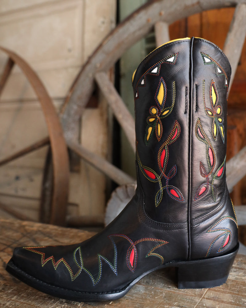 Black cowboy boot with colorful embroidery on a wooden surface
