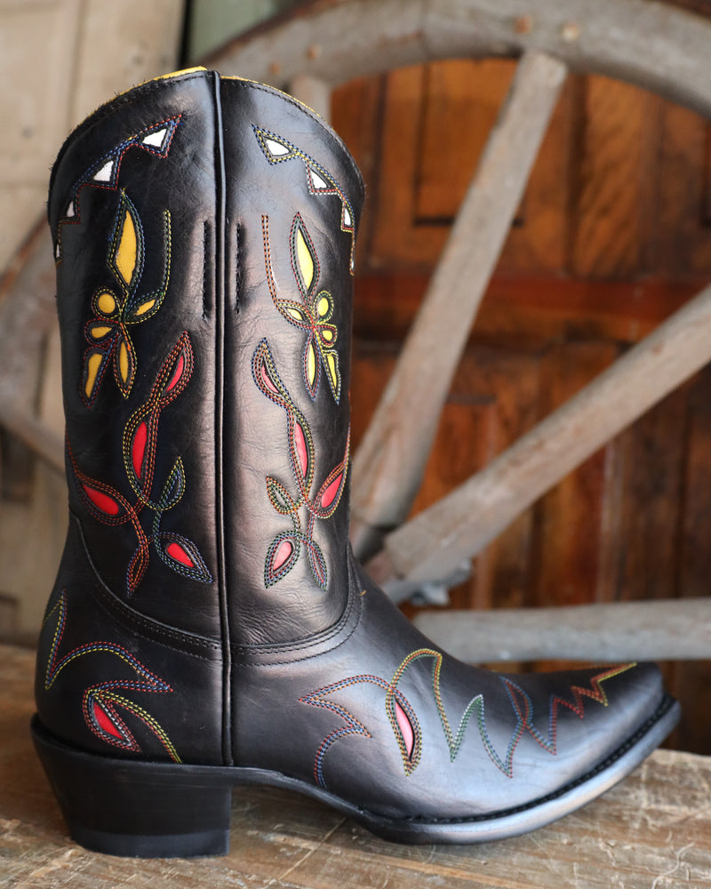 Black cowboy boot with colorful embroidery on a wooden surface