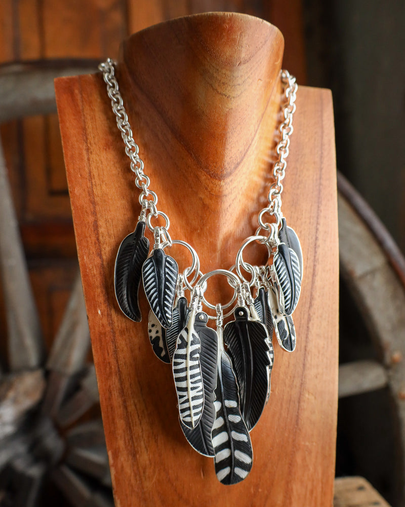 Necklace with feather-shaped pendants on a wooden stand