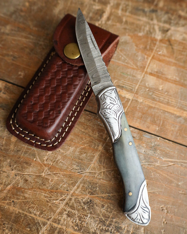 Knife with decorative handle and sheath on a wooden surface