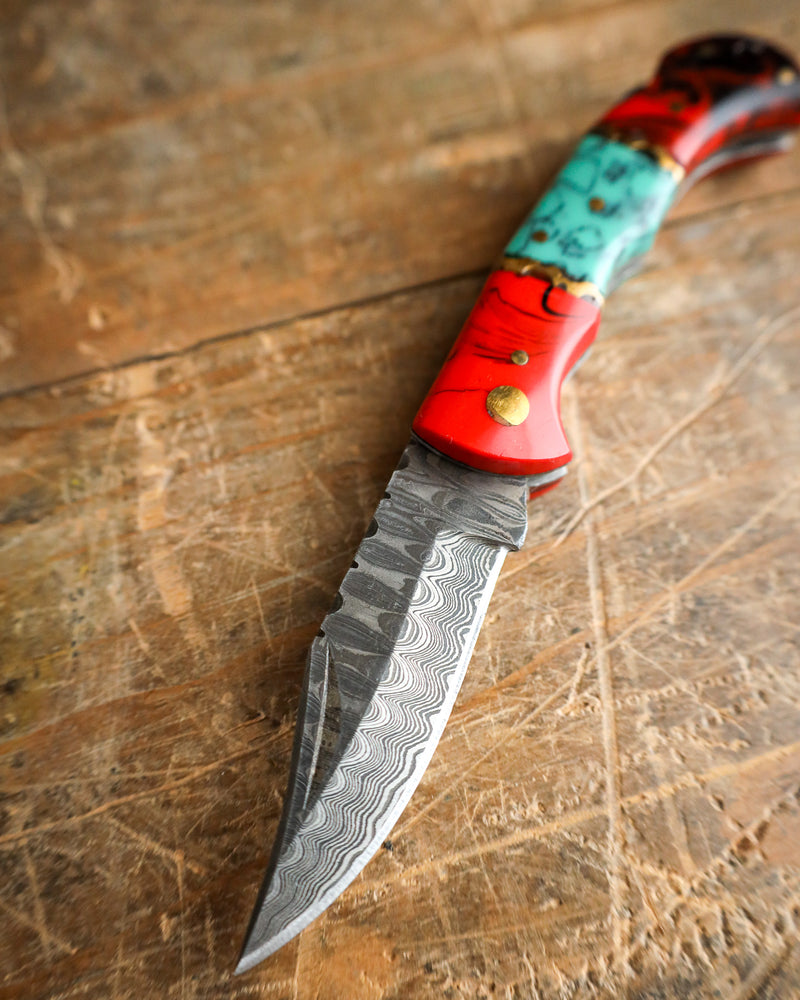 Decorative knife with a red and turquoise handle on a wooden surface