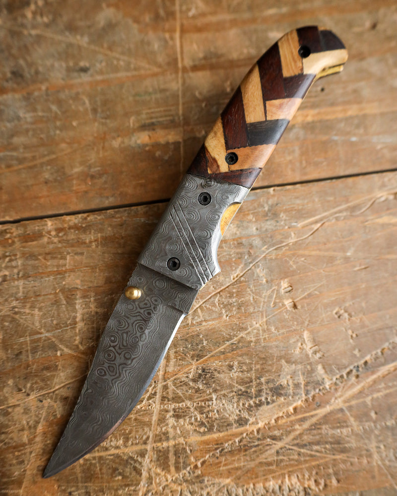 Folding knife with a wooden handle on a wooden surface