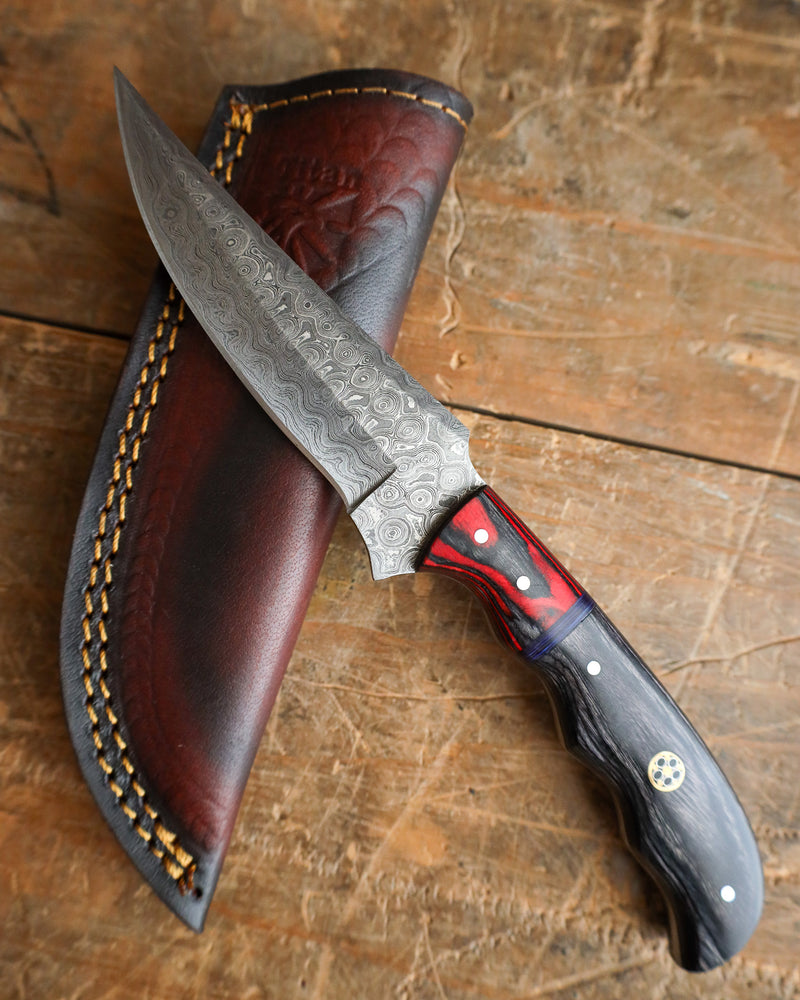 Decorative knife with a red and black handle on a wooden surface
