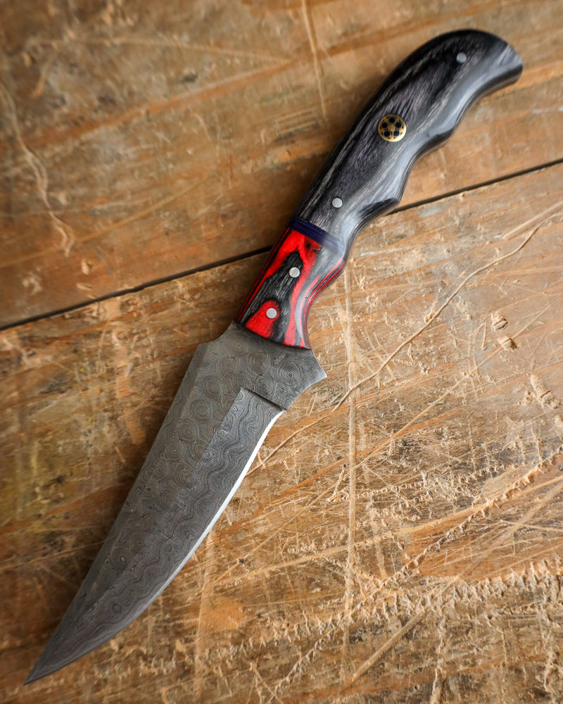 Knife with a black and red handle on a wooden surface