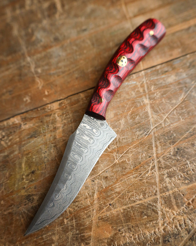 Knife with a red and black handle on a wooden surface
