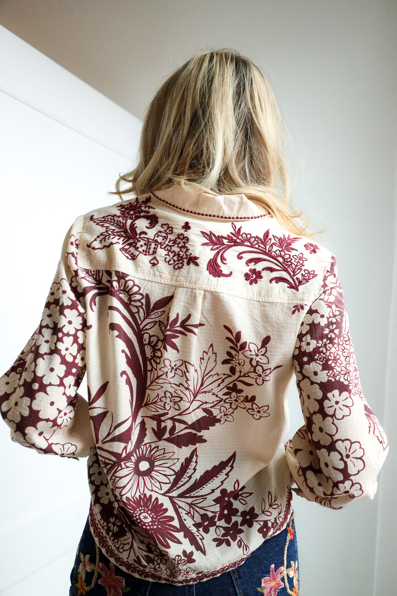 Person wearing a floral embroidered jacket with a neutral background