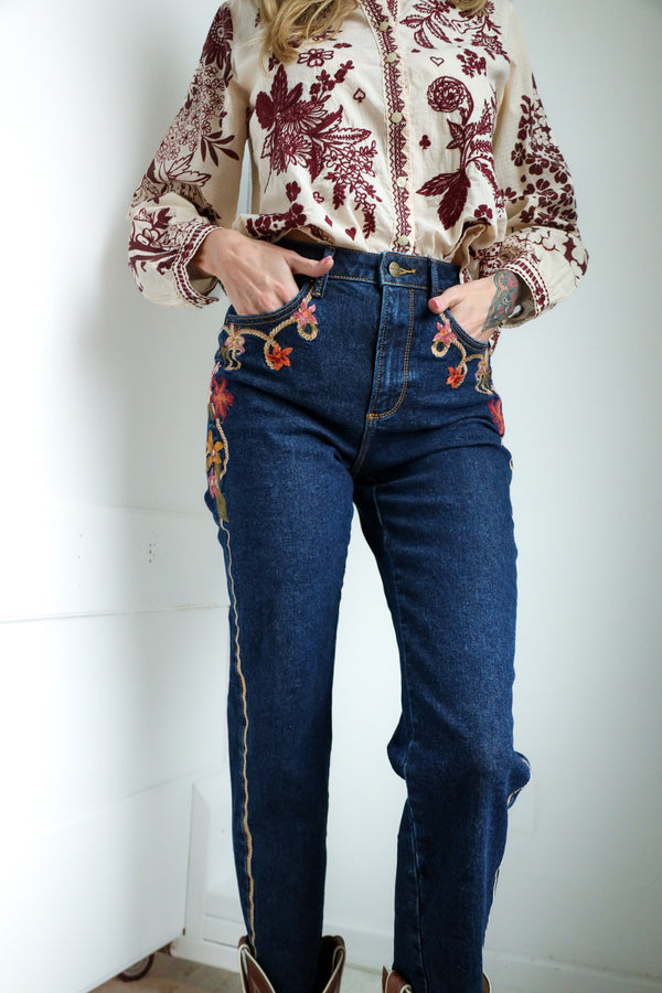 Person wearing a floral blouse and blue jeans against a white background