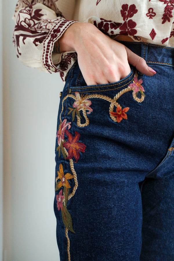 Blue jeans with floral embroidery on a plain background