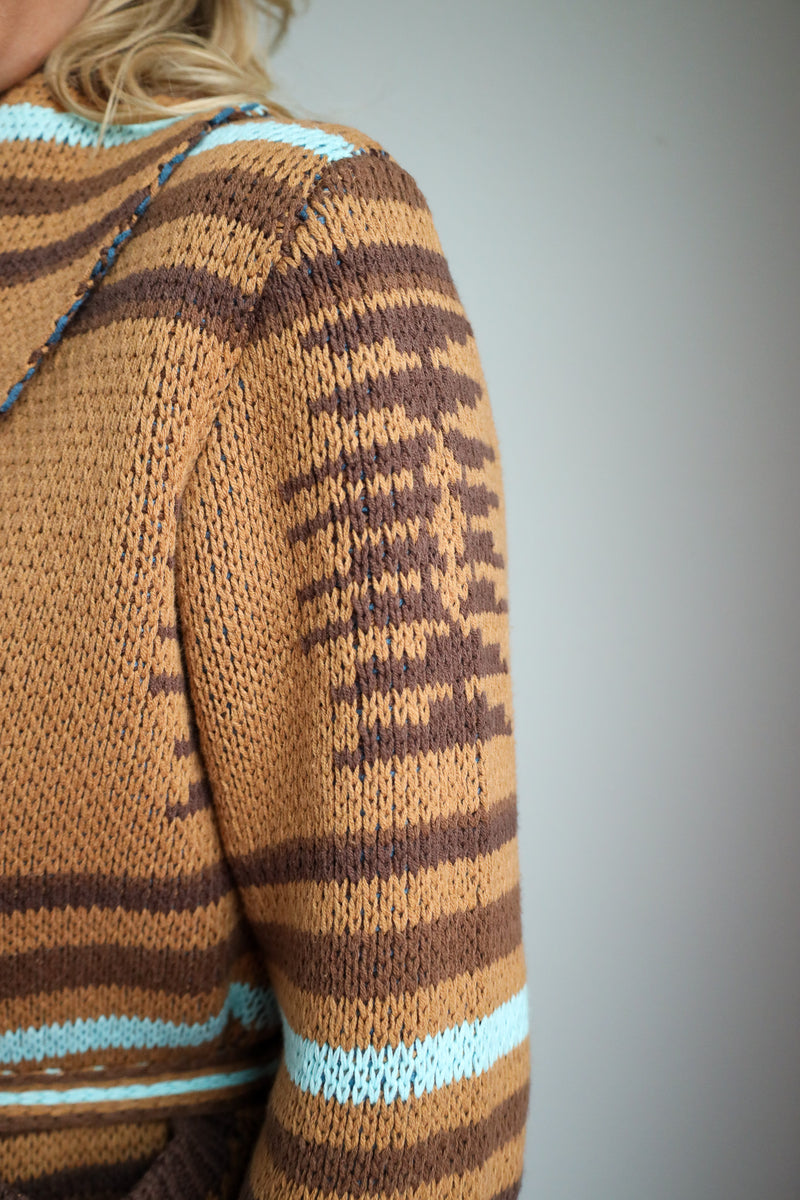 Close-up of a brown and blue striped sweater sleeve on a blurred background