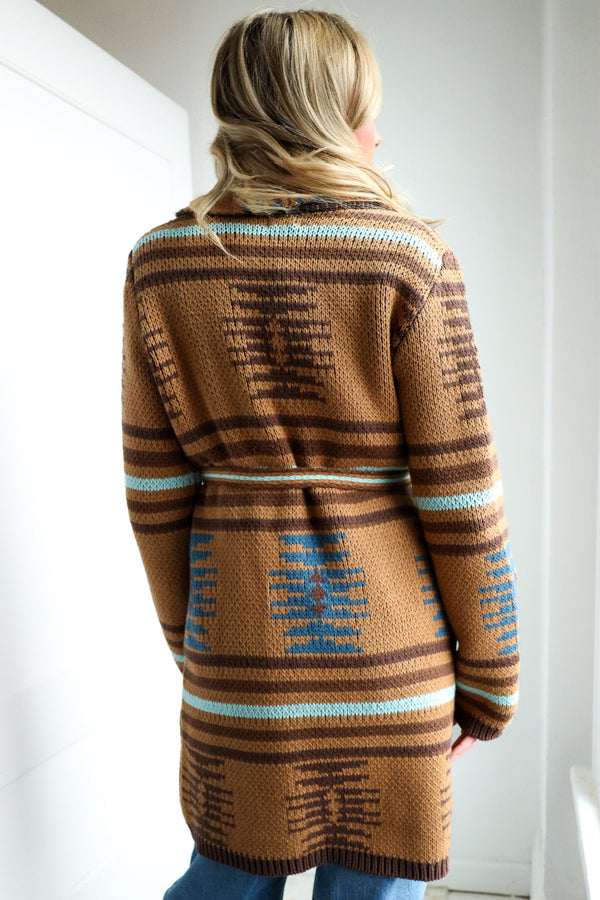 Person wearing a brown patterned sweater in a minimal indoor setting
