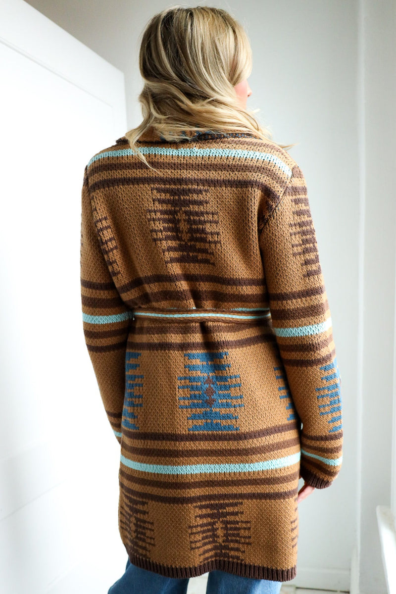 Person wearing a brown patterned sweater in a minimal indoor setting