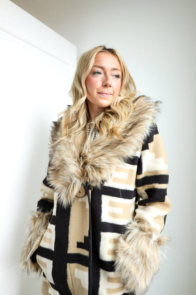 Woman wearing a patterned coat with fur trim against a white background