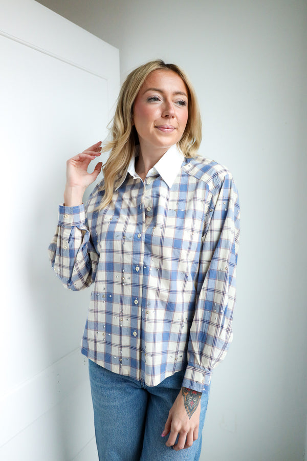 Woman wearing a blue and white plaid shirt against a plain background