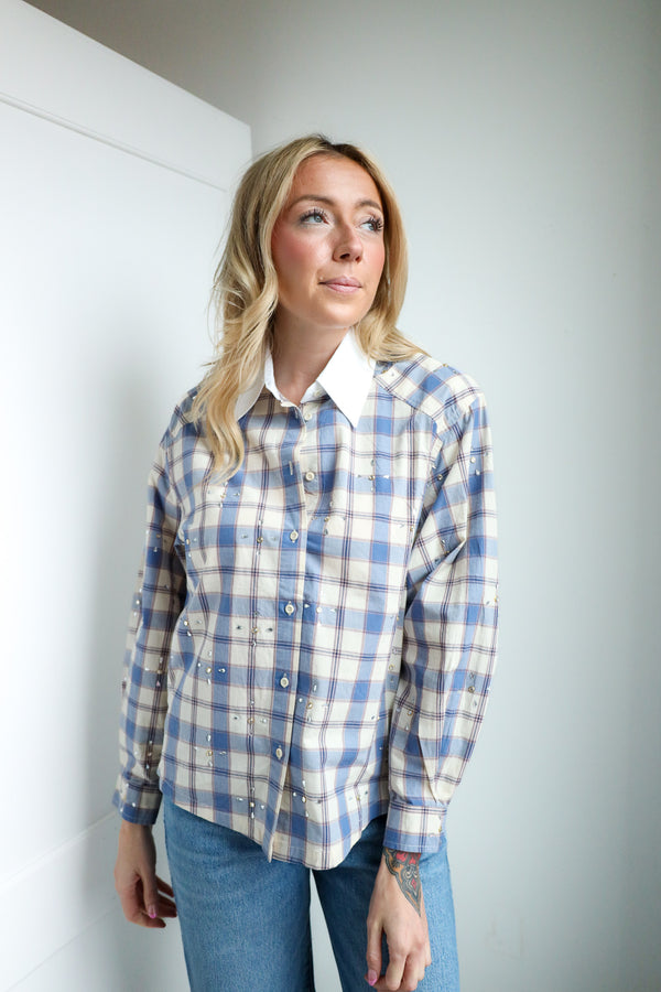 Woman wearing a blue and white plaid shirt against a plain background