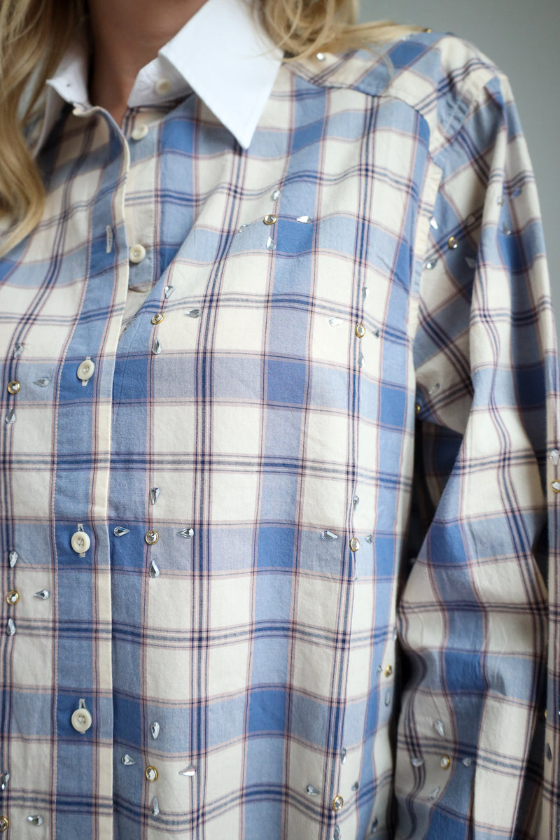 Close-up of a person wearing a blue and white plaid shirt.