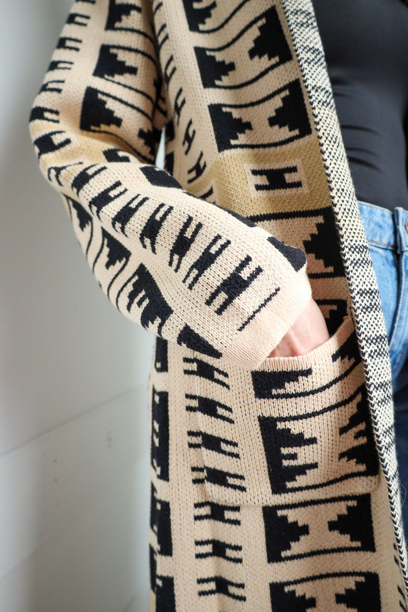 Person wearing a patterned cardigan with a neutral background